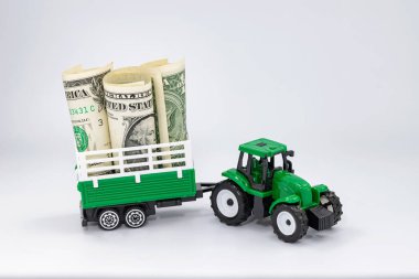 Yeşil oyuncak traktörü bir karavanda dolar taşıyor.