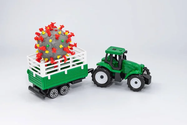 A toy farm tractor carries a 3D model of coronavirus made with a 3D pen in a trailer