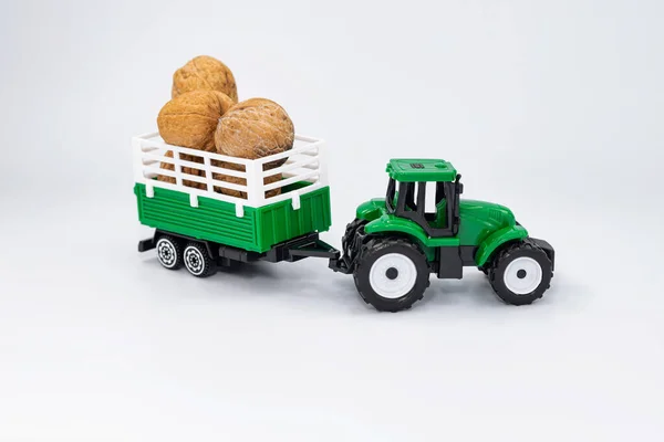 玩具农场的绿色拖拉机在拖车中运送核桃 — 图库照片