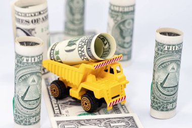 Sarı bir oyuncak kamyon bir dolar taşıyor.