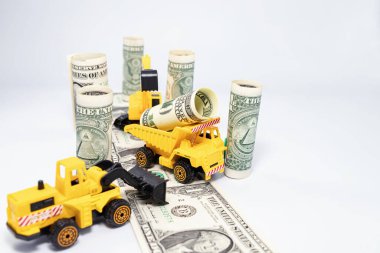 Oyuncak inşaat ekipmanları dolar banknotlarından yeni bir otoyol inşa ediyor.