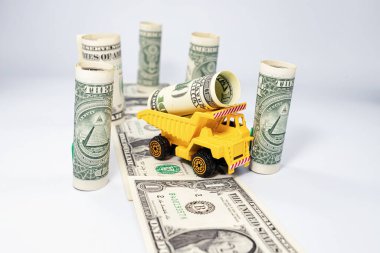 Sarı bir oyuncak kamyon bir dolar taşıyor.