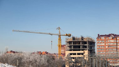 Sarı kule vinci olan çok katlı, tek katlı bir evin inşaatı.