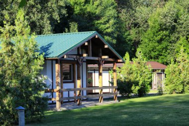 Kırsal bir dinlenme merkezindeki ahşap ev girişinde yeşil bir çim var.