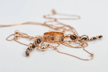 Yakut şeklinde yakutları olan altın bir yüzük, yakut küpeler ve beyaz yüzeye boncuklu altın bir zincir yansıtılır.