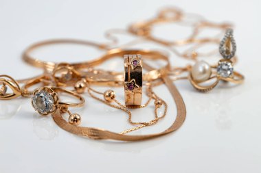 Yıldızlar şeklinde altın bir yüzük çeşitli şekillerde yakutlar ve altın zincirlerle süslenmiş ve beyaz yansıtıcı bir yüzey üzerine örülmüş.