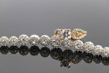 Elmas takılı zarif bir kadın yüzüğü değerli taşlı bir bileziğe takılır. Koyu arkaplan