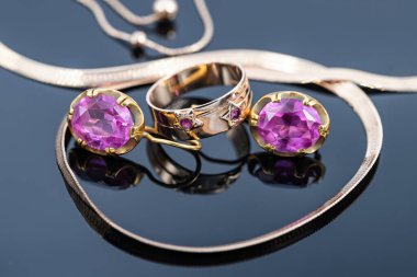 Yıldızlar şeklinde kabartma şeklinde geniş altın bir yüzük yakutlarla işlenmiş küpeler ve yılan derisi dokumalı bir zincir.