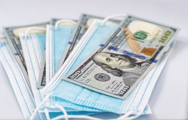 Tek kullanımlık koruyucu maskeler ve 100 dolarlık banknotlar.