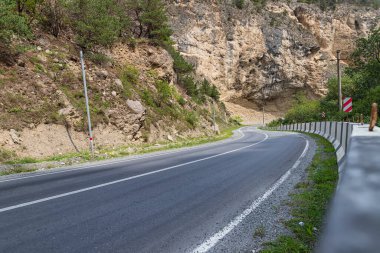 Dağlık bir bölgede beton bariyeri olan asfalt bir yol.