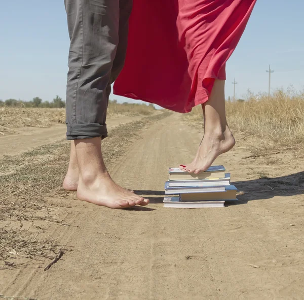 Een meisje staat op een stapel boeken te bereiken en de kerel kus — Stok fotoğraf