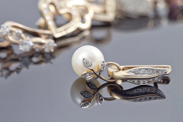Conjunto de pendientes decorativos de oro con anillo adornado con perlas en la superficie reflectante —  Fotos de Stock