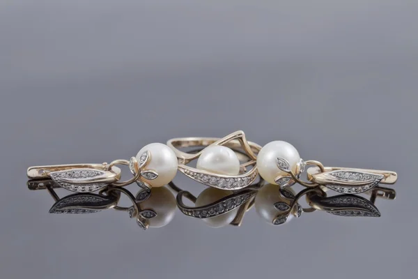 镶有装饰的金耳环戒指点缀的反射面上的珍珠 — 图库照片