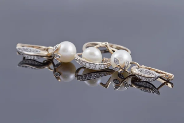 Conjunto de pendientes decorativos de oro con anillo adornado con perlas en la superficie reflectante —  Fotos de Stock