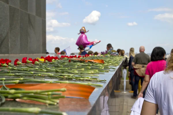 Laying red carnations at the foot of the sculpture of the Mother — Stock Photo, Image