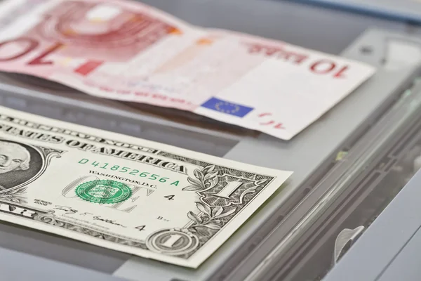 Las denominaciones de un dólar y diez euros se encuentran en el escáner — Foto de Stock