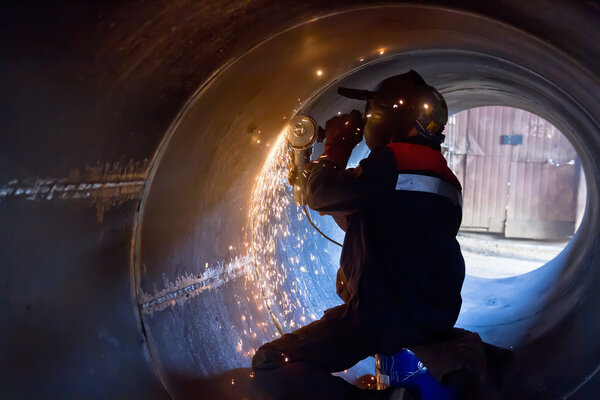 welder carries out mechanical cleaning of root surfaces of weld
