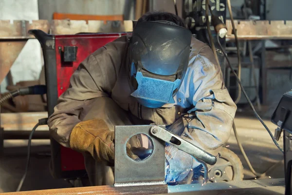 Um soldador fabrica estruturas de aço usando soldadura semi-automática — Fotografia de Stock