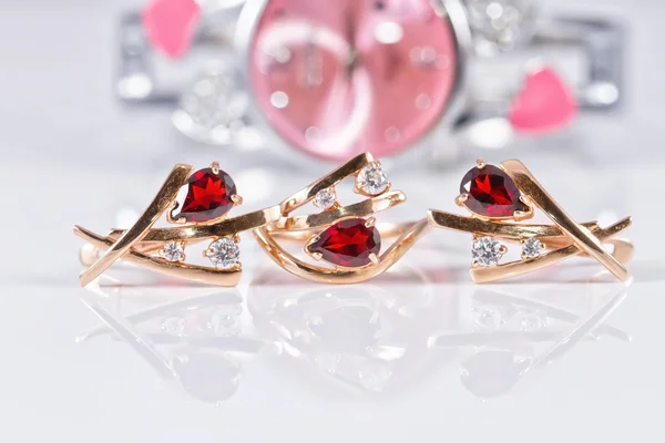 Gold earrings with rubies and elegant women's watches — Stock Photo, Image