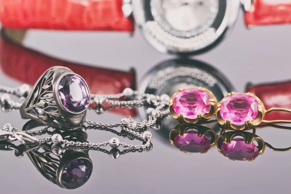 Gouden oorbellen en ringen met rood robijnen en horloge — Stockfoto