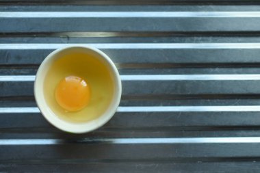 Lavabonun zemininde bir fincanda çiğ tavuk yumurtası.