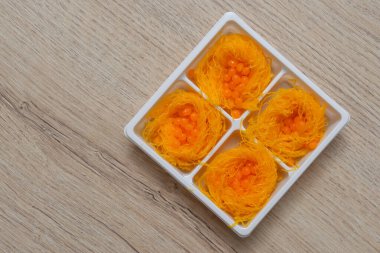 Foi Thong, tahta bir masada plastik bir kutuda tatlı yiyor.