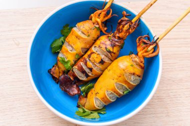 Ahşap masadaki mavi kasede ızgara kalamar.