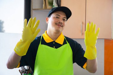 Profesyonel erkek temizleyici modern mutfağı dezenfekte ediyor, tezgah ve aletleri temizleyip hijyenik ve güvenli bir yemek ortamı sağlıyor..