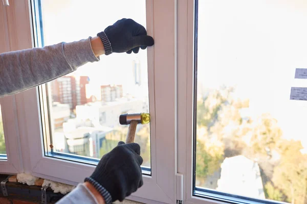 A worker installs a new plastic window in the living room.