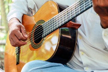 İnsan 'ın akustik gitar çalarkenki görüntüsünü kapat 