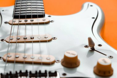 Turuncu arka planda Beyaz Elektrikli Gitarın Detayları.