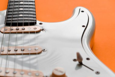 Turuncu arka planda Beyaz Elektrikli Gitarın Detayları.