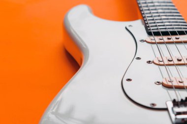 Turuncu arka planda Beyaz Elektrikli Gitarın Detayları.