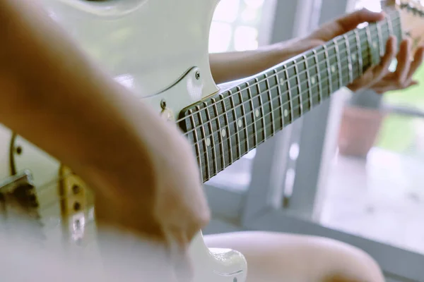 Woman hands playing electric guitar close up