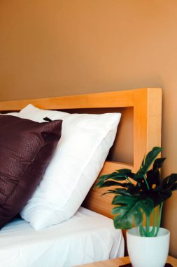 Yatak odasında yapay bitki süsü. Modern beyaz yatak ve yastık sabah modunda.