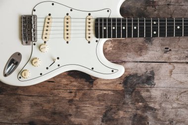 Ahşap arka planda Beyaz Elektrikli Gitarın Detayları.