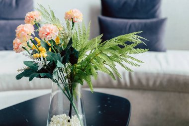 Oturma odasındaki masa dekorasyonunda pembe çiçek vazosu..