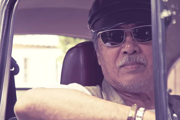 Пожилой мужчина в очках за рулем автомобиля — стоковое фото