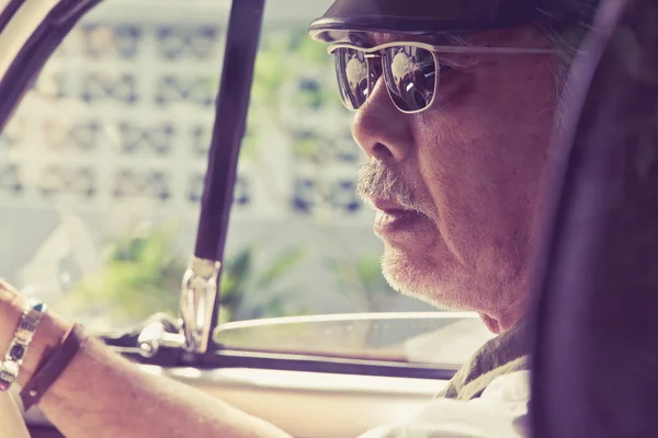 Older man with glasses driving a car — Stock Photo, Image