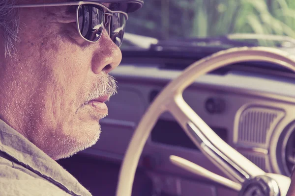 Older man with glasses driving a car — Stock Photo, Image