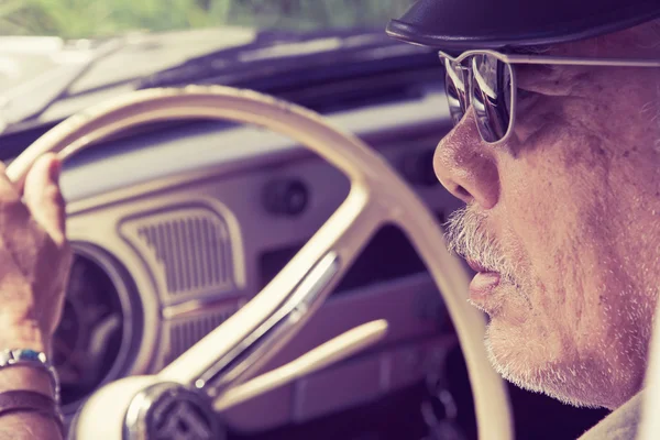 Older man with glasses driving a car — Stock Photo, Image