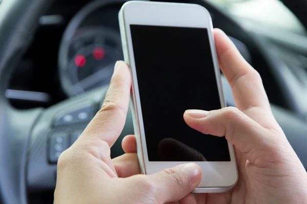 Young woman holding mobile device in the car