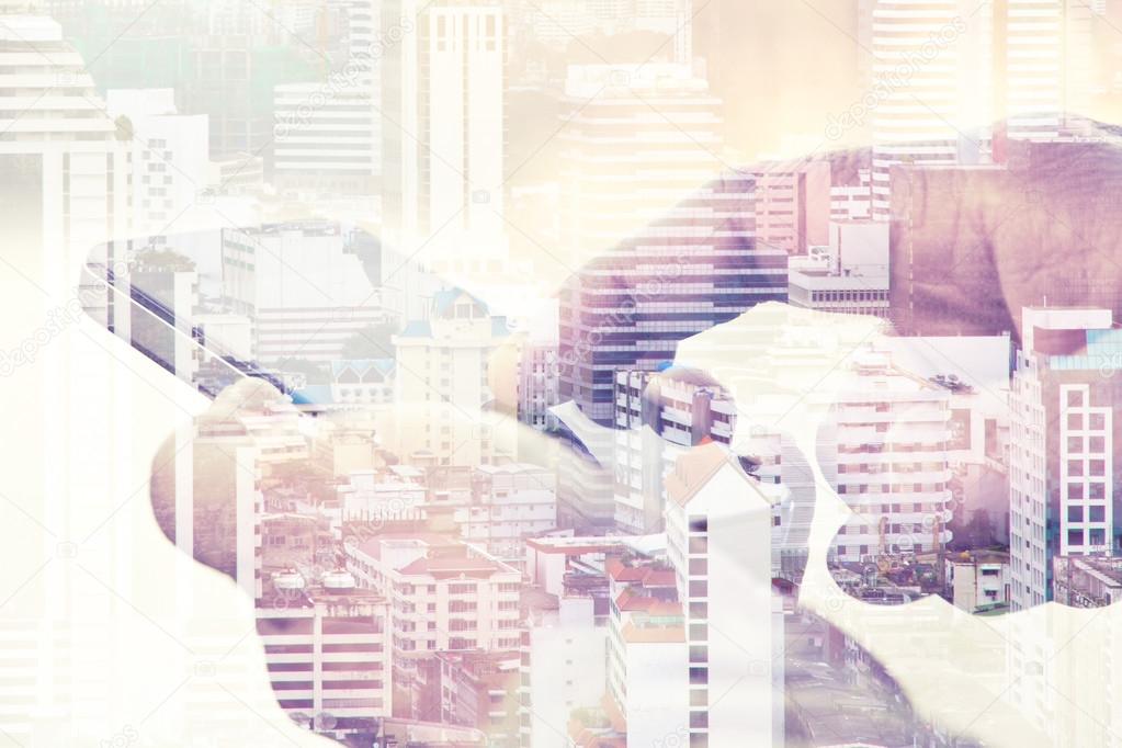 Double exposure of man using a smart phone with a view of the city