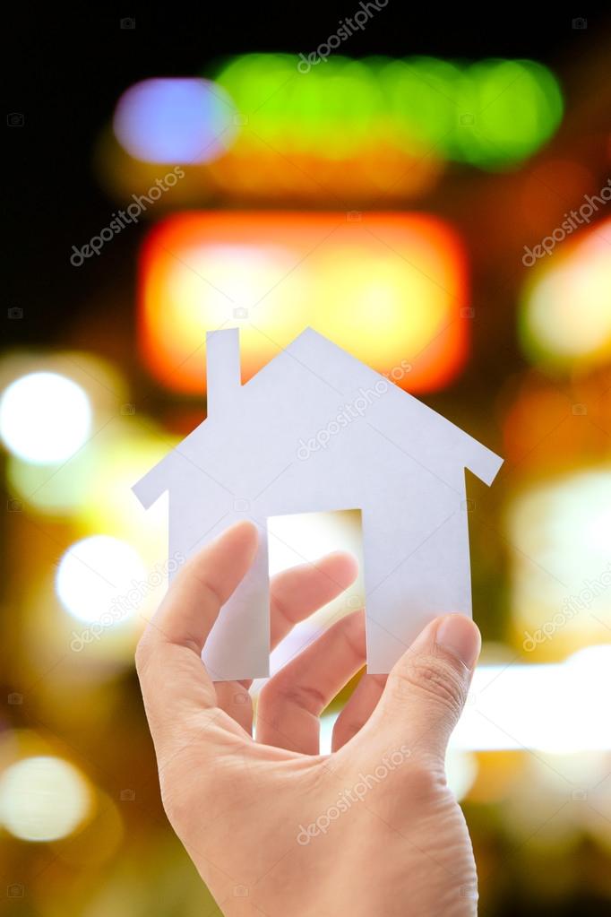 hand holding icon house concept with defocused city night light background