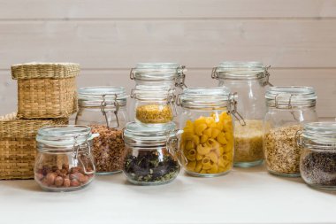 Tahta masadaki cam kavanozlarda pişmemiş tahıl, tahıl ve makarna çeşitleri. Sağlıklı yemek, temiz yemek, sıfır atık kavramı..
