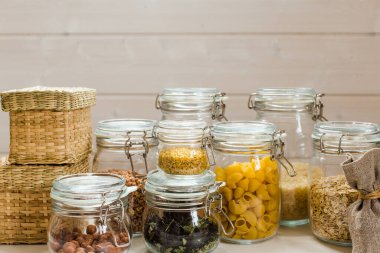 Tahta masadaki cam kavanozlarda pişmemiş tahıl, tahıl ve makarna çeşitleri. Sağlıklı yemek, temiz yemek, sıfır atık kavramı..