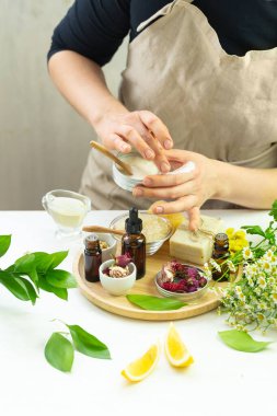 Bitkiler, çiçekler, limon, yağlı kadın elleri gibi organik doğal içerikli el yapımı krem.