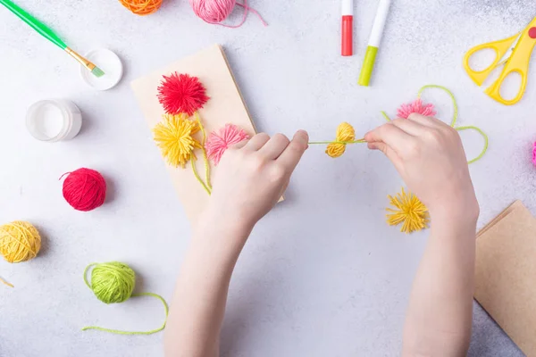 Küçük çocuk renkli kağıttan bir buket çiçek yapıyor ve annesi için renkli örgü topları örüyor. Basit bir hediye fikri. Üst görünüm, boşluk kopyala — Stok fotoğraf