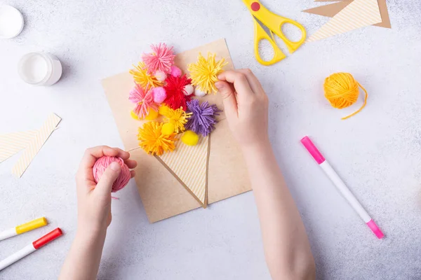 Egy kisgyerek virágcsokrot készít színes papírból és színes kötőgolyókat anyának. Egyszerű ajándék ötlet. nézet felső, másolás tér — Stock Fotó