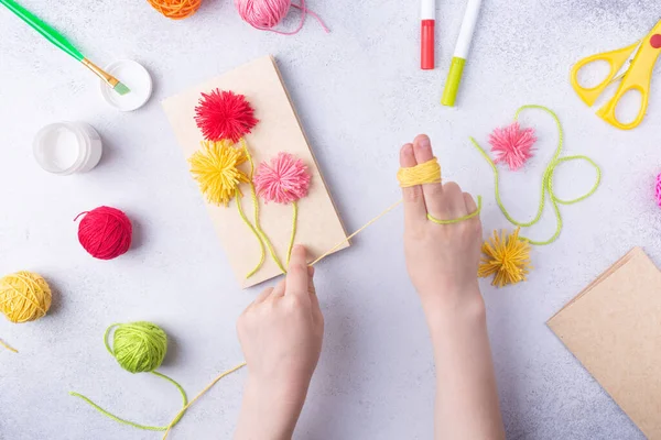 Malé dítě dělá kytici květin z barevného papíru a barevných pletených míčků pro mámu. Jednoduchý nápad. pohled shora, místo pro kopírování — Stock fotografie